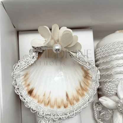 Close up image of the 3 piece baptism candle set shell, embroidered in white nylon thread, and white flower with white bead and rhinestone.