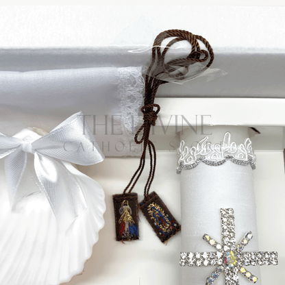 Close up image of the 6 piece baptism candle set showing white candle, shell with white ribbon, white crystal beaded rosary, and bible covered in fabric with nylon thread embroidered, and scapular with Divine Mercy and Our Lady of Guadalupe image, and fabric towel. 