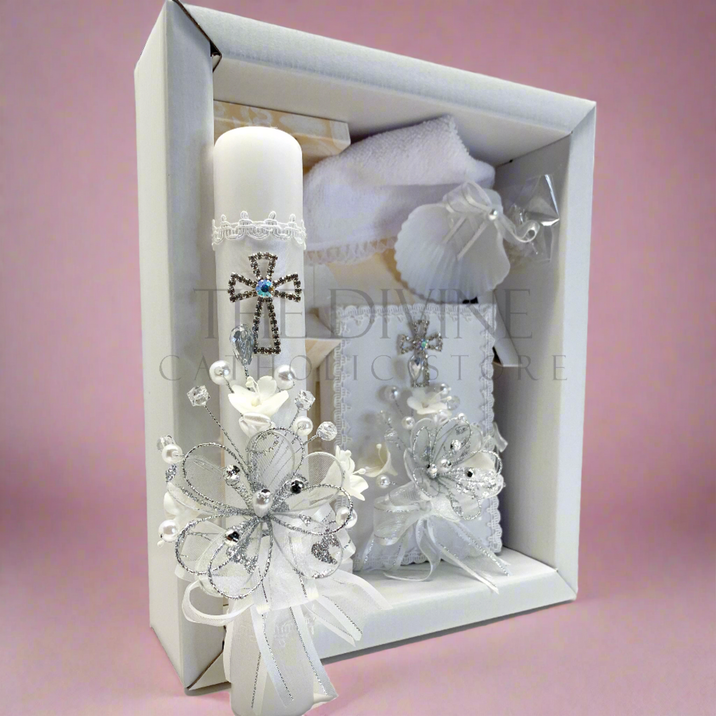 The image features a beautifully designed 5-piece baptism candle set, including a candle, a towel, rosary, bible, and a shell. The candle is adorned with white fabric, a braided nylon rope, small white flowers, and rhinestone embellishments, giving it an elegant and sacred look, with pink background.